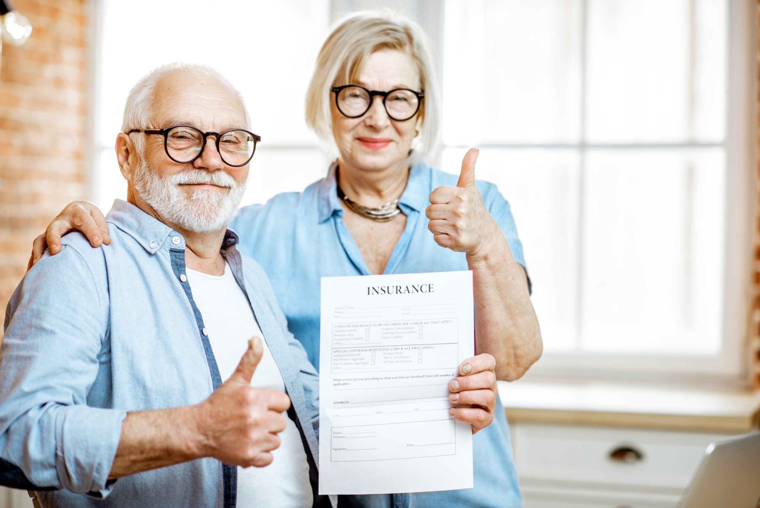 Elderly couple holding insurance document, giving thumbs up.