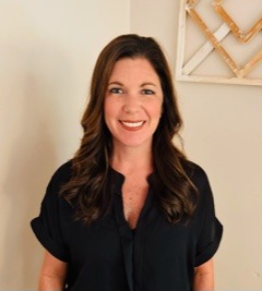 Smiling woman in black blouse against neutral background.